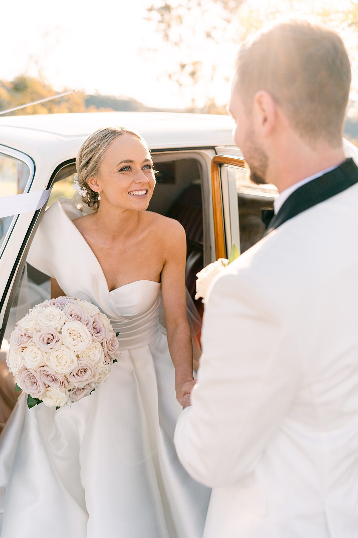beautiful image of bride holding the groom's hand in an antique car