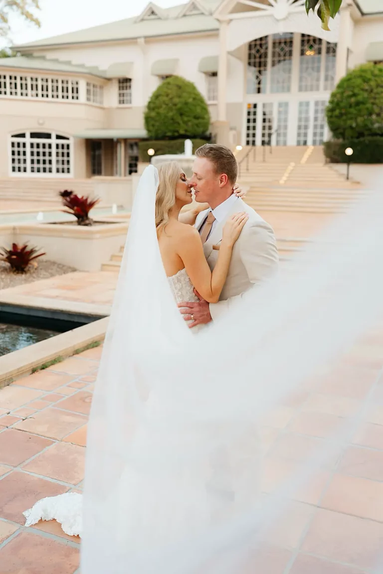 bride and groom kissing with veil flying in the wind