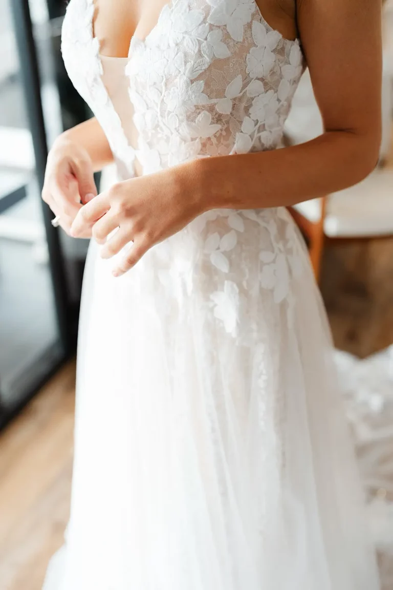 elegant wedding dress details with bride holding her hands