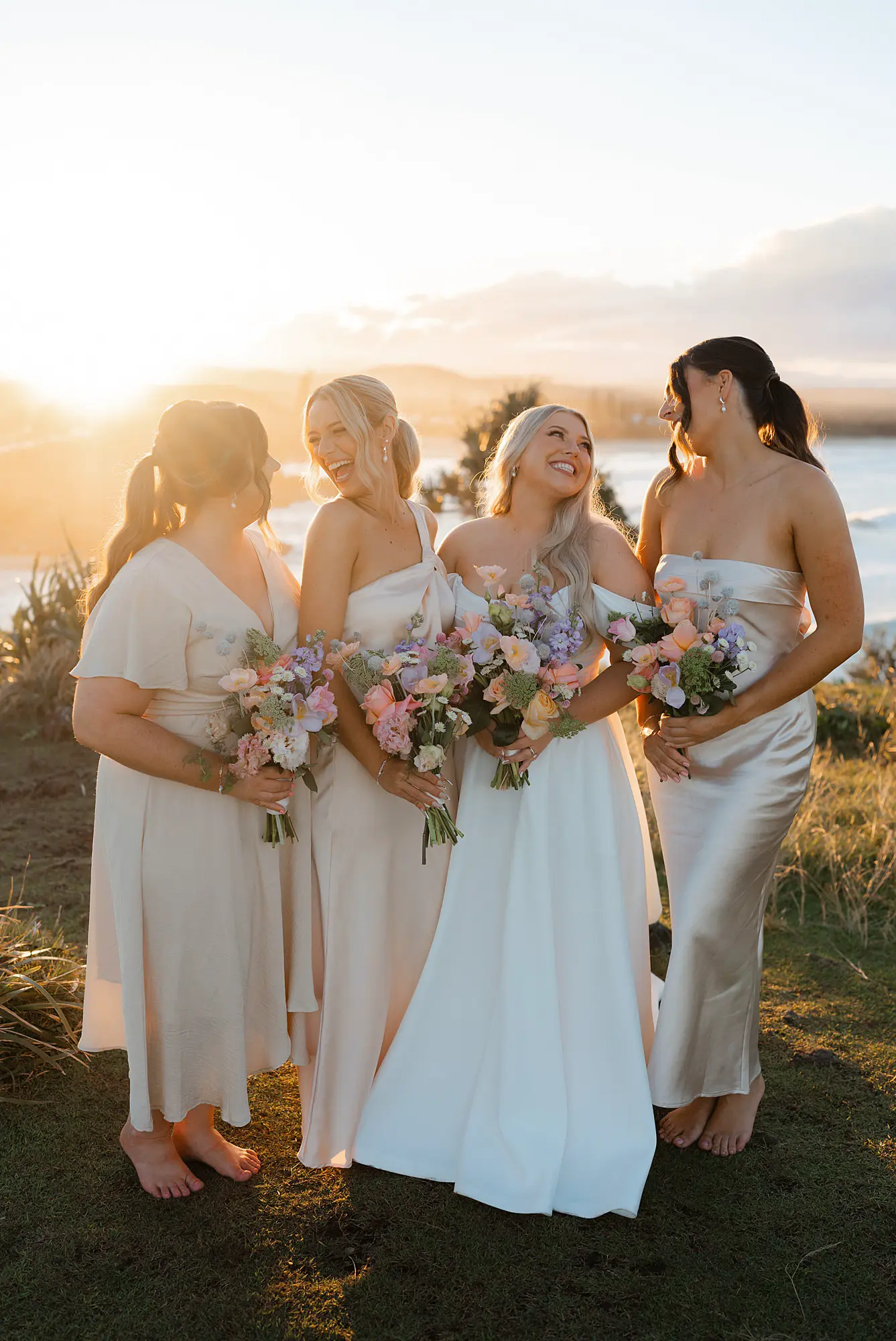 bride and her bridesmaid smiling at each other during their wedding portraits